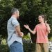 happy teenage boy showing big gesture with hands near bearded father in park