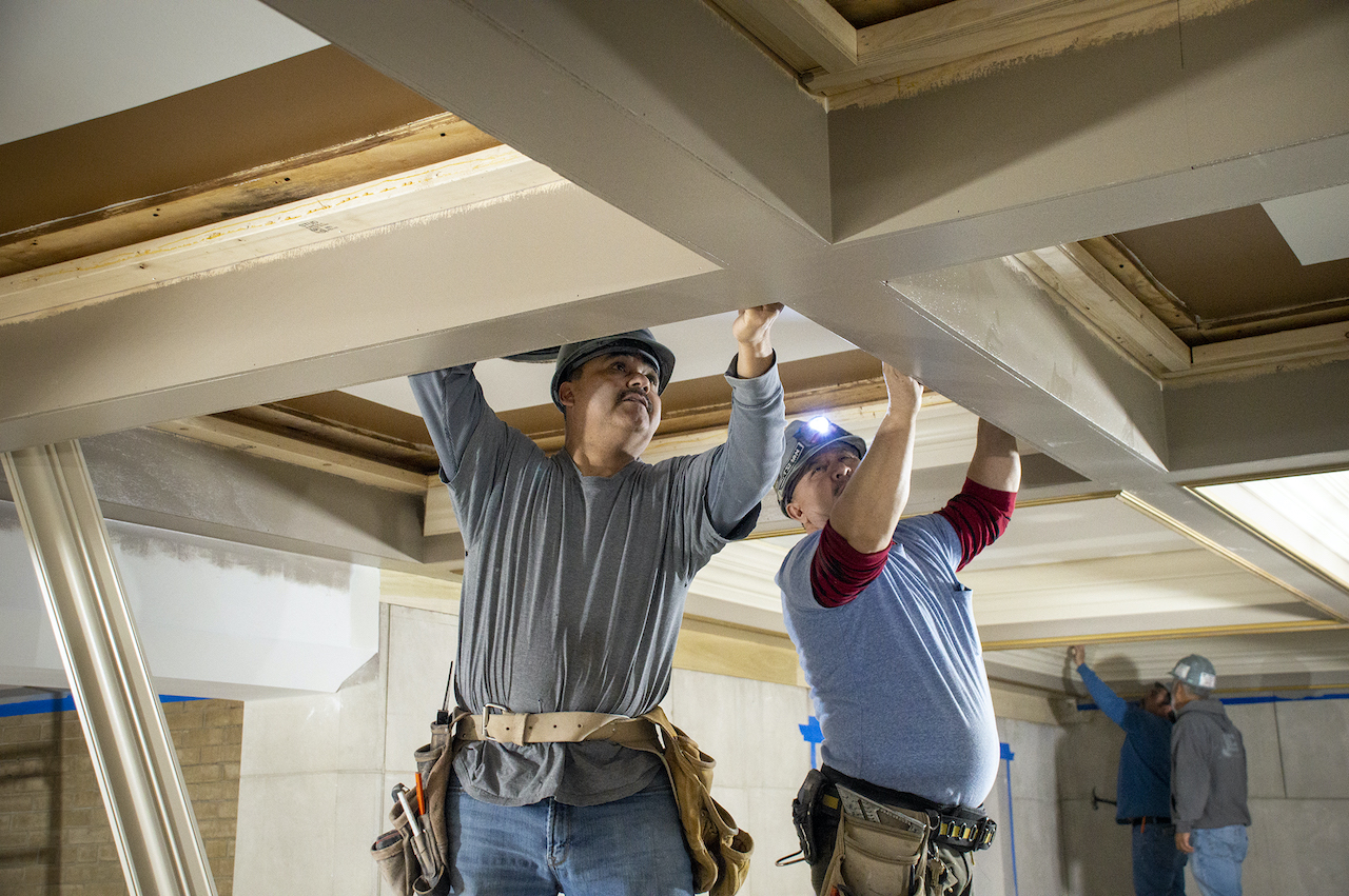 Cięcie belek sufitowych piłą łańcuchową na budowie Cięcie drewnianej belki sufitowej piłą łańcuchową przez pracownika na rusztowaniu