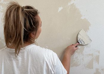 Wiadro farby glinkowej do ścian obok świeżo pomalowanej białej ściany w salonie