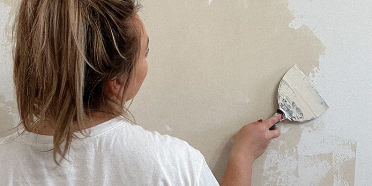 Wiadro farby glinkowej do ścian obok świeżo pomalowanej białej ściany w salonie