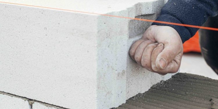 Stos białych bloków betonu komórkowego z porowatą strukturą na placu budowy