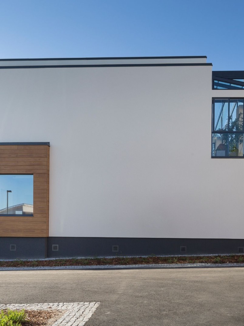 Aplikacja wałkiem farby fasadowej silikonowej Ręce malarza nakładające farbę silikonową wałkiem na tynkowaną ścianę zewnętrzną