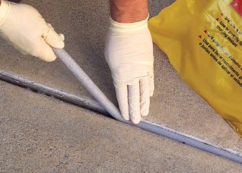 Robotnik naprawiający pęknięcie w betonowej podłodze garażu podczas remontu domu