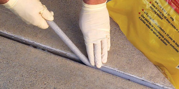 Robotnik naprawiający pęknięcie w betonowej podłodze garażu podczas remontu domu