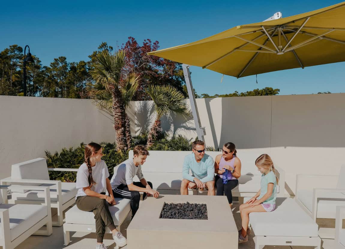 Stalowe palenisko z drewnem na żwirze Stalowe okrągłe palenisko z rusztem i płonącymi polanami otoczonymi żwirem dekoracyjnym