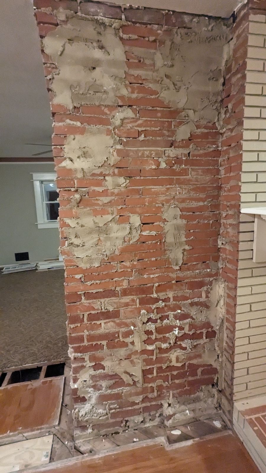 poziomowanie zaprawy kielnią na cegle murarz poziomuje kielnią świeżą zaprawę między dwiema cegłami