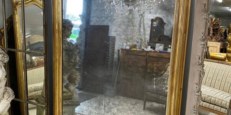 stara sypialnia z dużym antycznym lustrem w złoconej ramie na ścianie