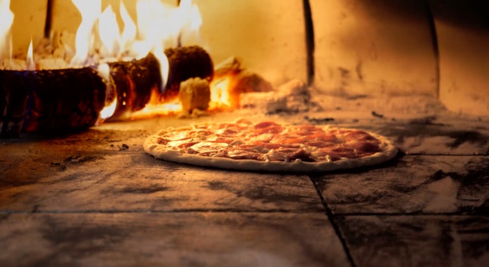 ręce pizzaiolo formują ciasto na drewnianej desce